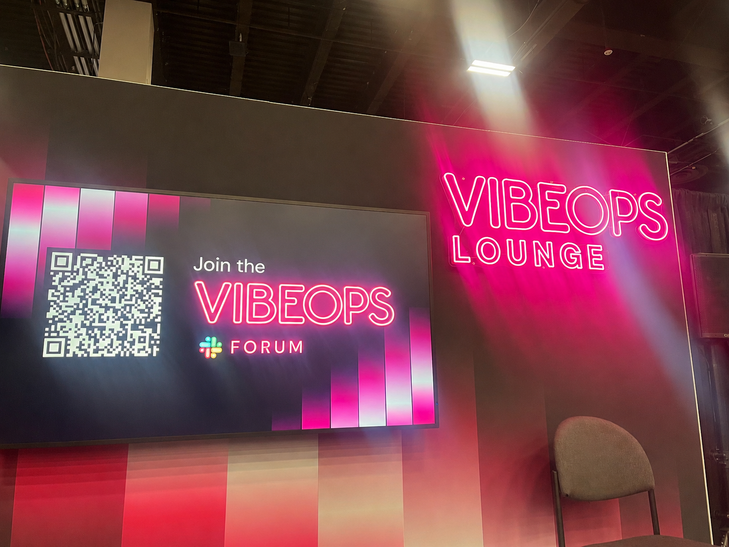VIBEOPS Lounge neon sign with a screen inviting people to join the VIBEOPS Forum